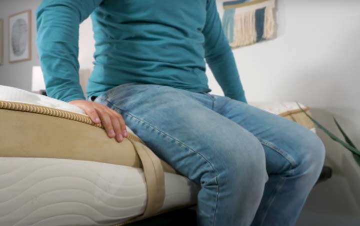 A man sits near the edge of the Loom and Leaf mattress.