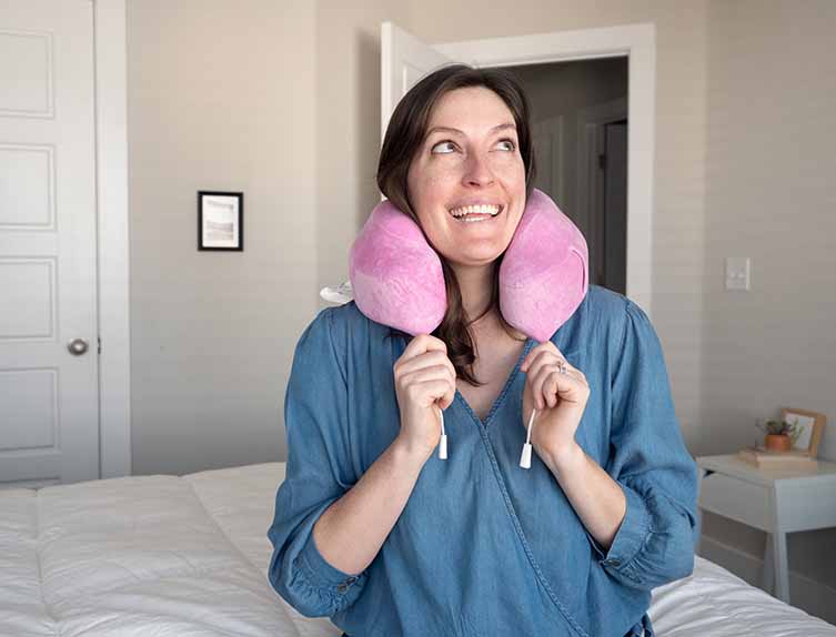 woman using a pink Cabeau Evolution Classic travel pillow
