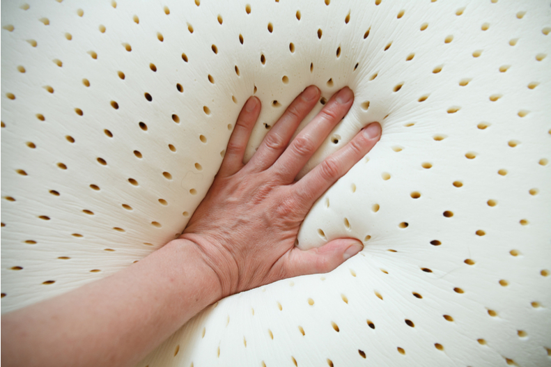 A hand pushes into a soft mattress.