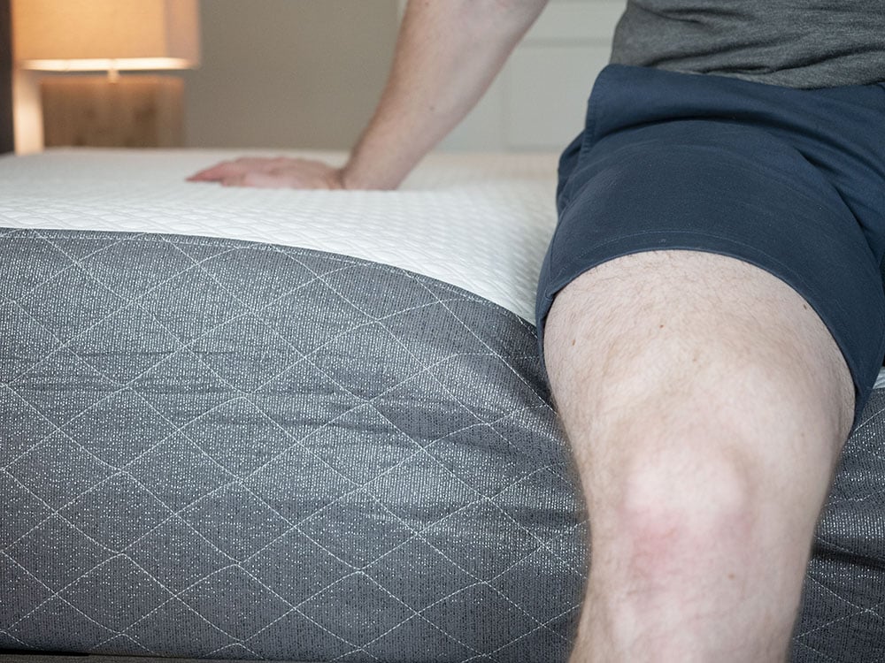 A man sits on the edge of the bed.