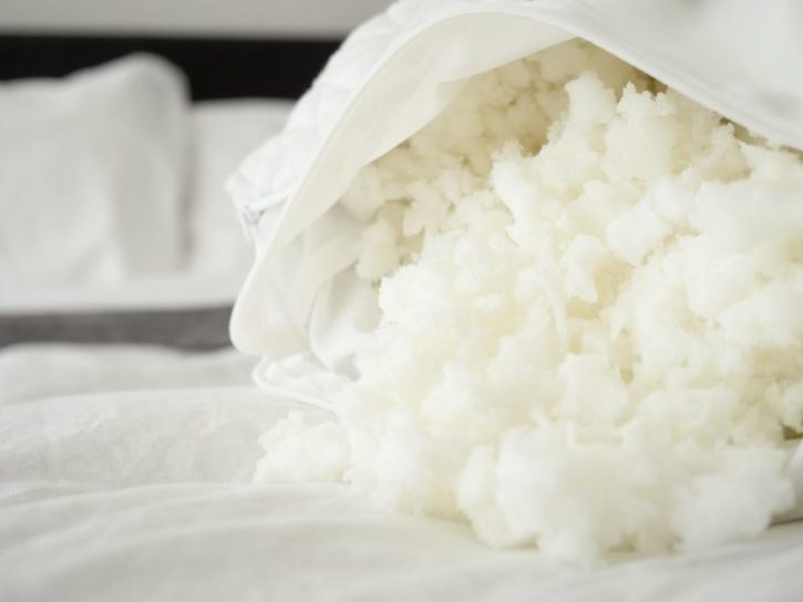 The filling of a Coop Home Goods Original Pillow spills across a bed. 