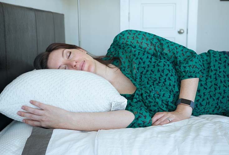 A woman sleeps on her side using the Snuggle-Pedic Adjustable Foam pillow.