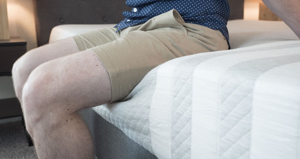 A man sits near the edge of the bed.