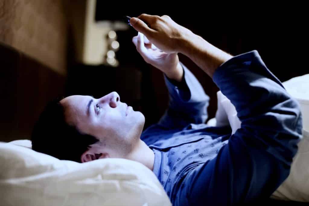 A man looks at his phone in bed