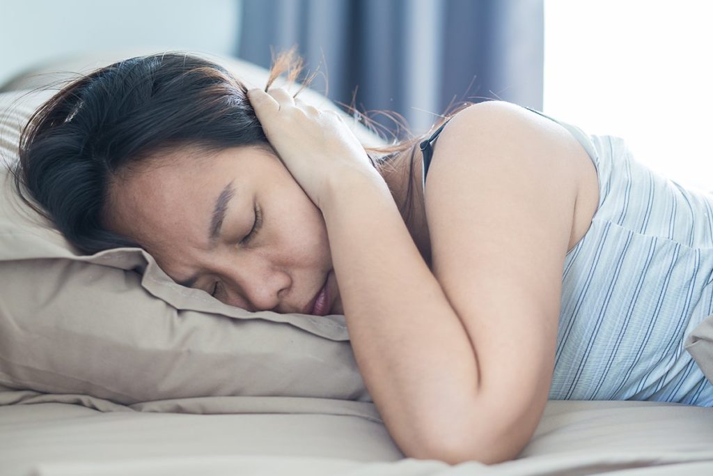 a woman sleeps with her ears covered