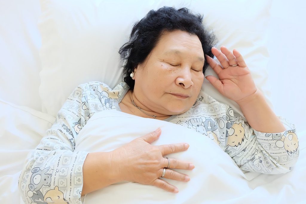 A woman sleeps on her bed.