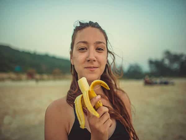 woman eating a banana on the beach