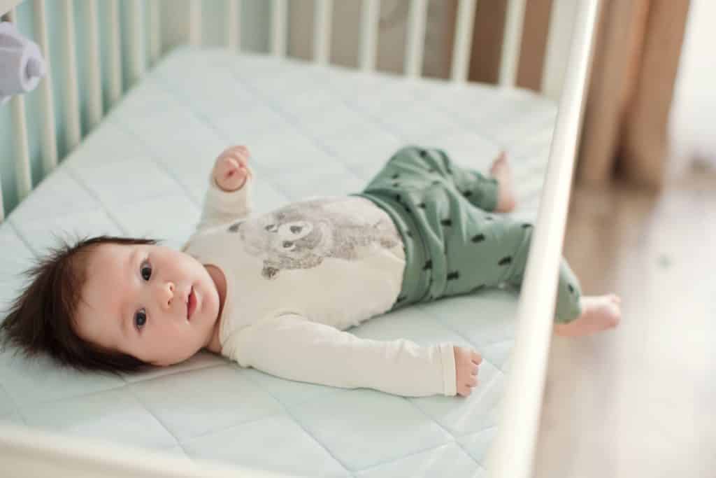 Baby laying on crib mattress