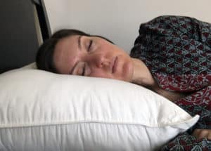 A woman rests her head on the Brooklinen Down Alternative Pillow.