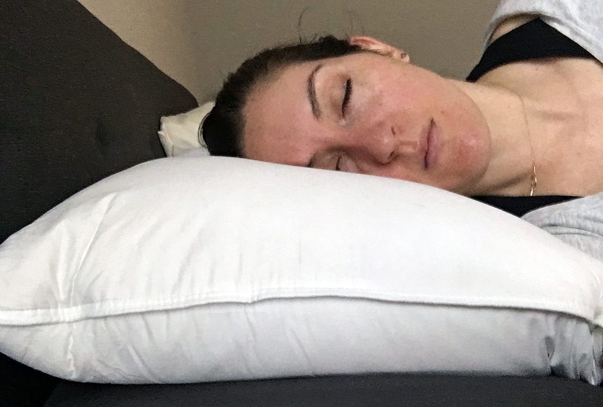 A woman rests her head on the Brooklinen Down Pillow.