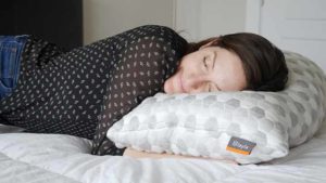 A woman sleeps on her side with the Layla Kapok Pillow