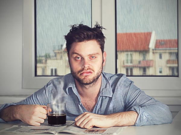 A man looks tired and holds his coffee.