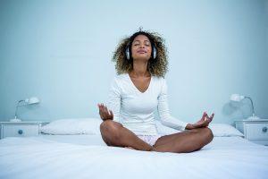 woman meditating on bed to help improve sleep