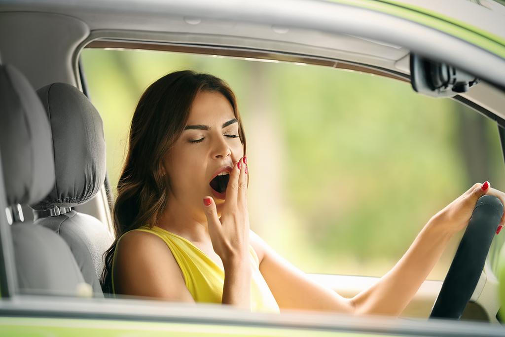 A woman yawns in her car