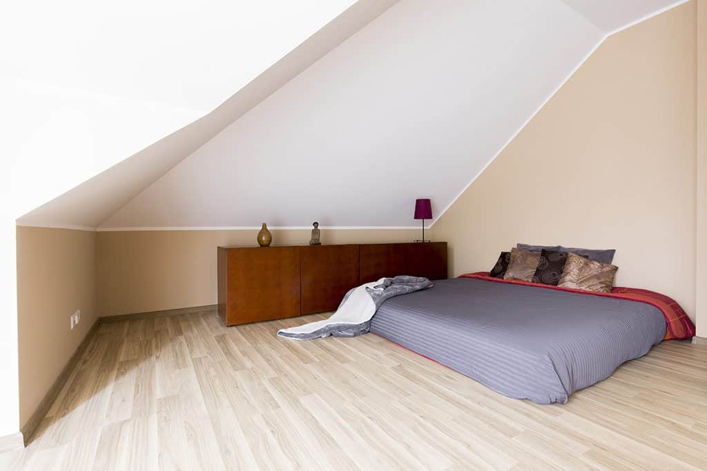 A mattress with sheets on the floor of a bedroom