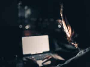 A man looks at his computer in the dark.