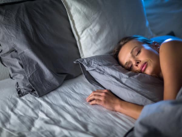 A woman lies down on blue bedding.