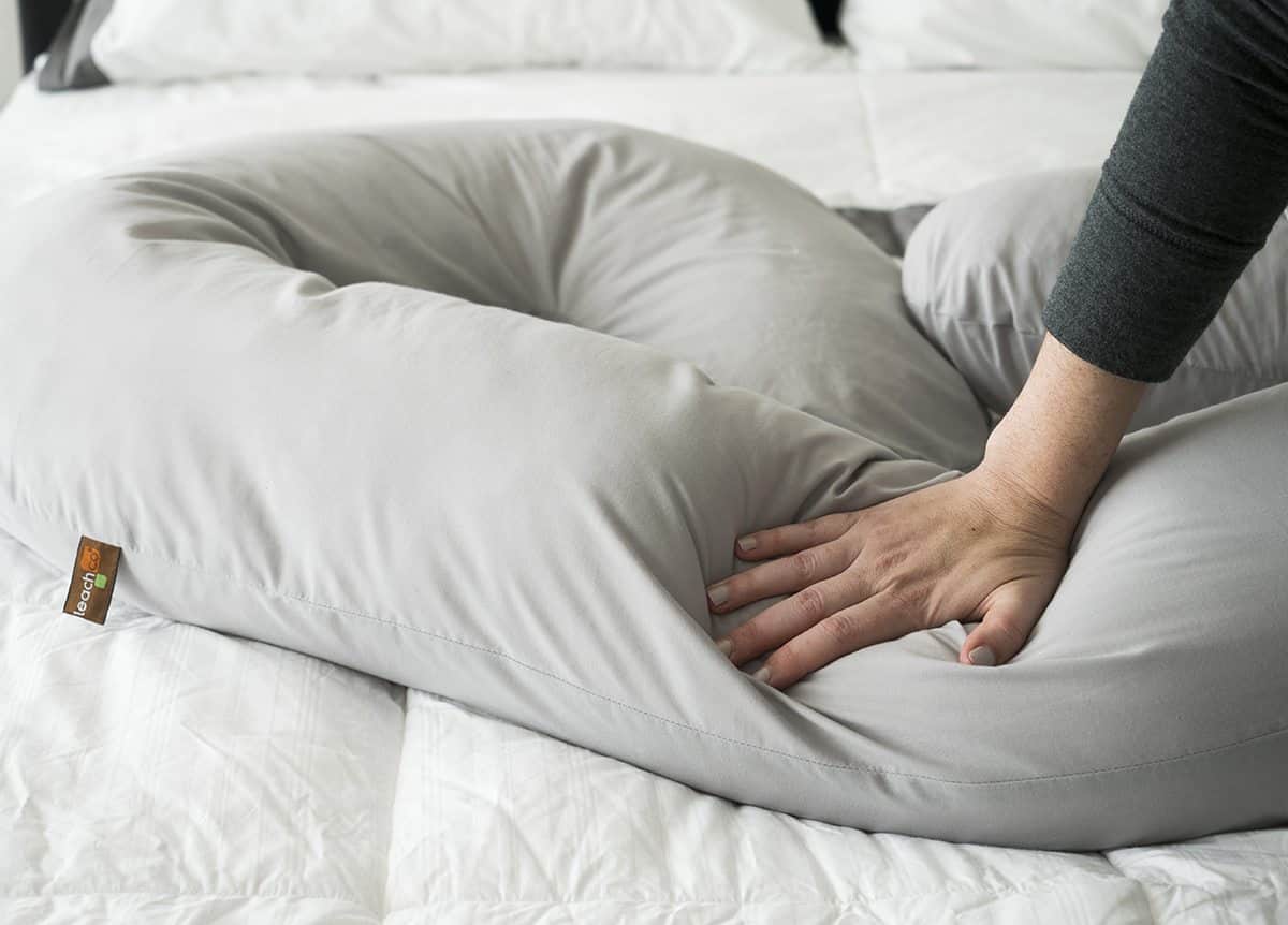 a woman presses into the Leachco Snoogle pregnancy pillow