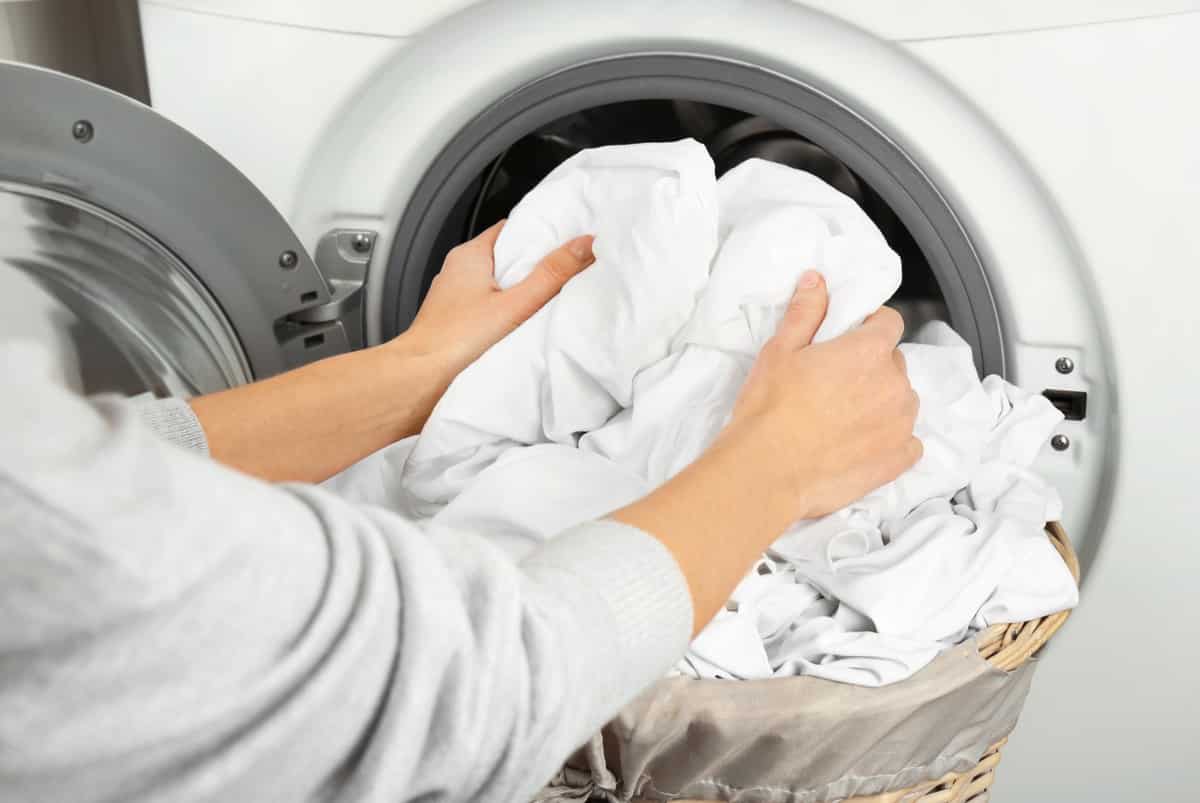 the best sateen sheets - a picture of a woman putting sheets into the washing machine