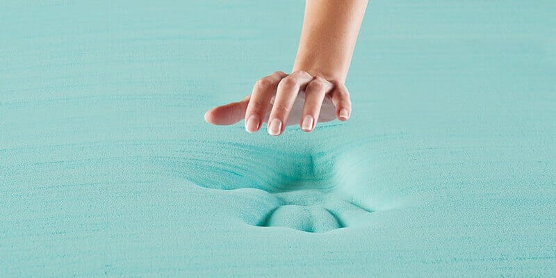 An image of a hand above memory foam, which shows an impression of the hand.