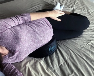 A pregnant woman rests with the Hiccapop wedge pillow under her belly.