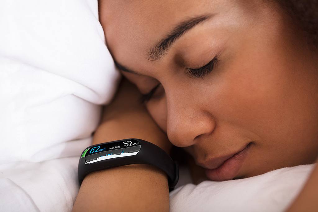 A woman sleeps with a sleep tracker on her wrist