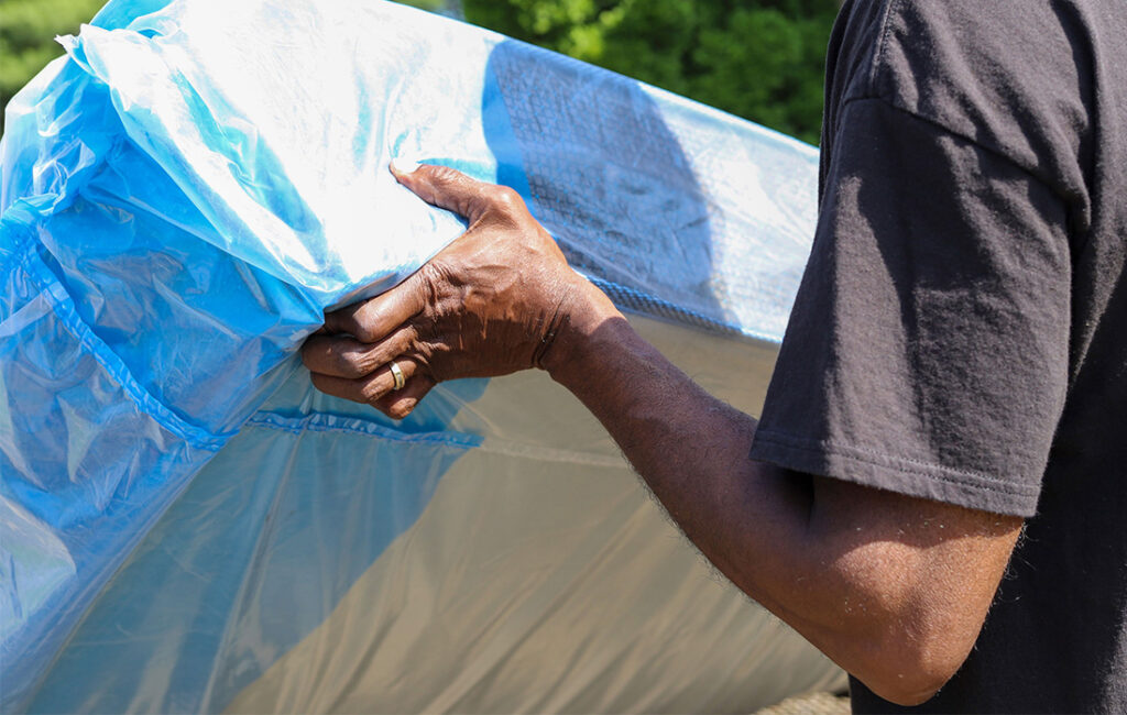 A man moving a mattress covered with a protective bag