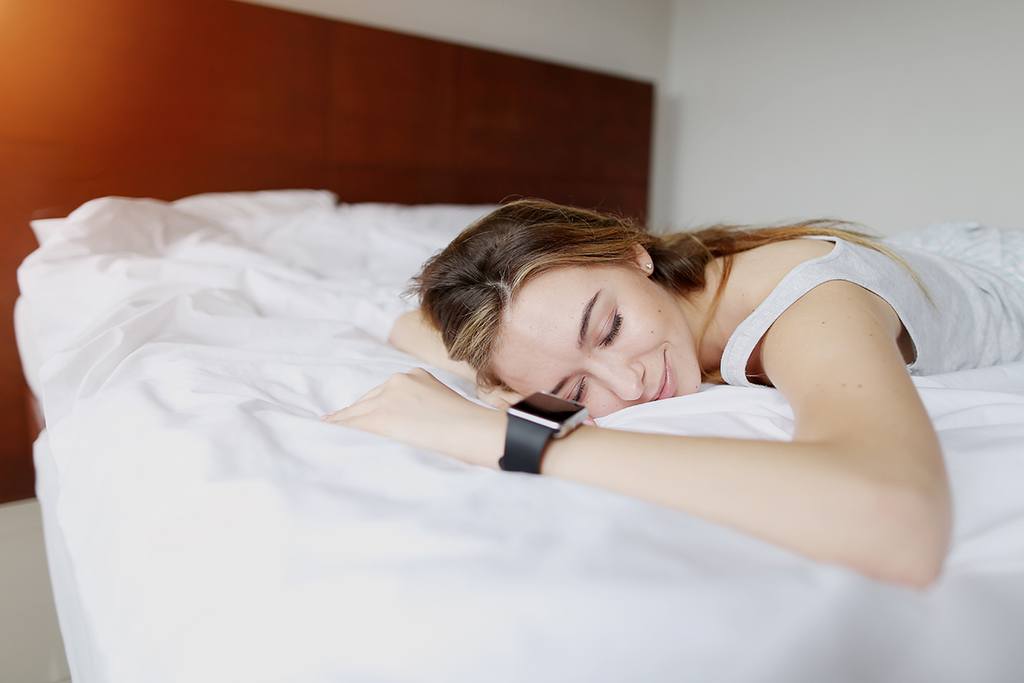 a woman sleeps with a sleep tracker on her wrist