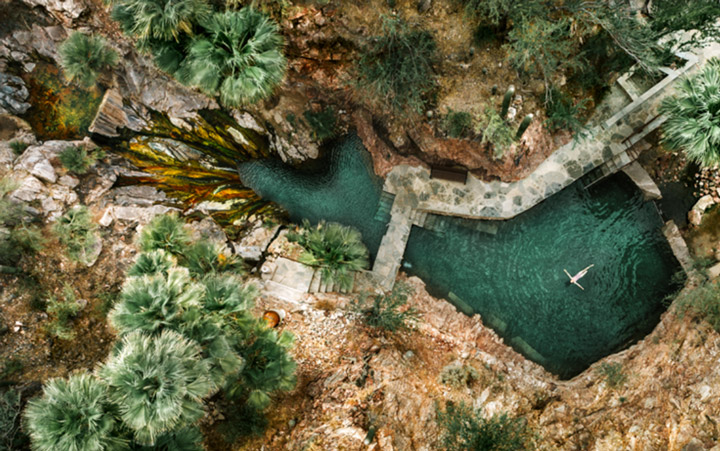 An overhead shot of a woman floating in hot springs
