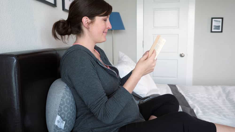 woman reading with a pregnancy pillow on her back