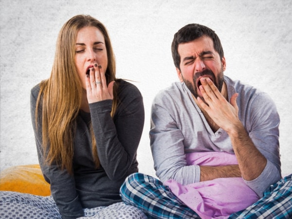Two people yawn in bed.