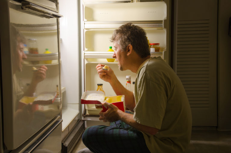 Man eating in front of fridge