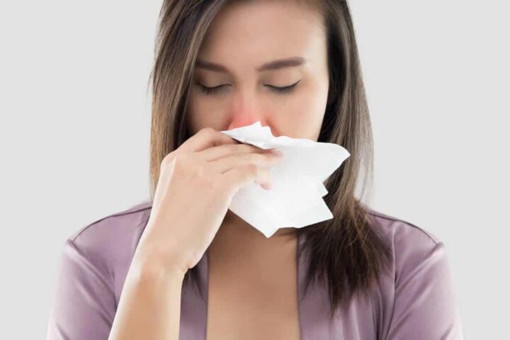 A woman blows her nose into a tissue