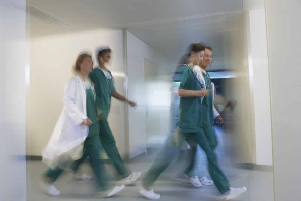 Physicians rush down a hallway.