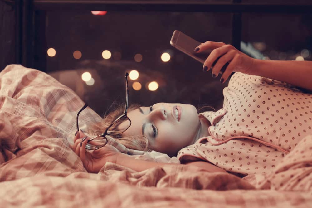 A young woman looks at her phone at night.