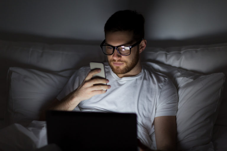 Man looking at screens in bed