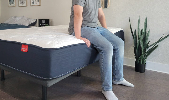 A man sits near the edge of the Big Fig mattress