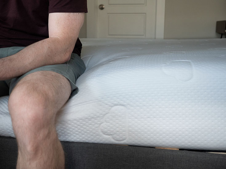 A man sits on a foam mattress.