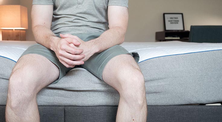 A man sitting on the edge of the bed.