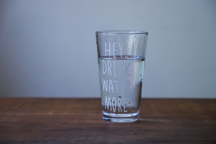 a glass of water with the words "hey drink water more" on the glass