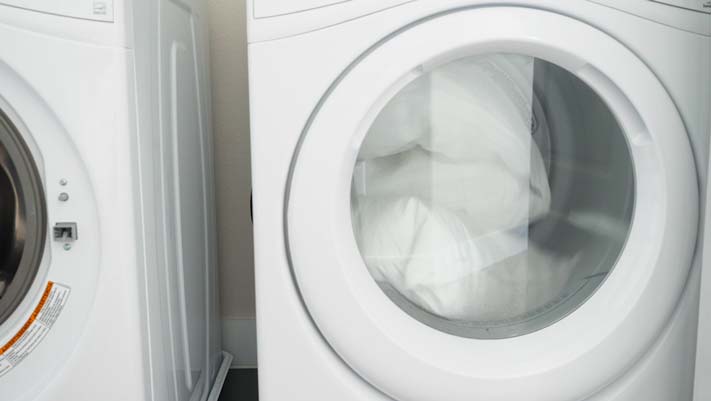An image of a dryer with a white topper cover inside.