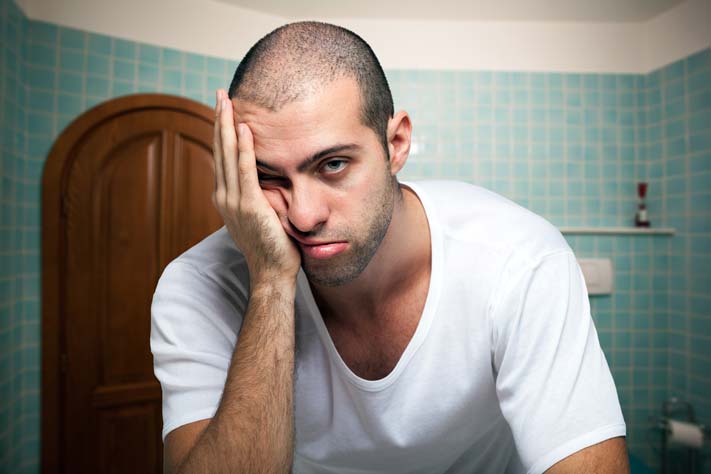 A stressed man rubs his head