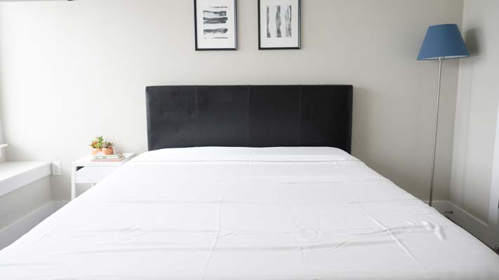 bed with sheets on dark bed frame