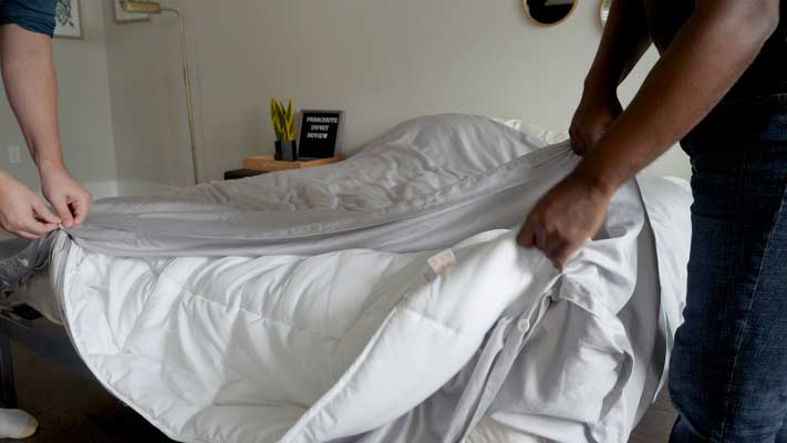 Two men put on a duvet cover.