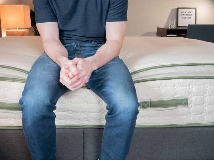 A man sits on the edge of the bed.