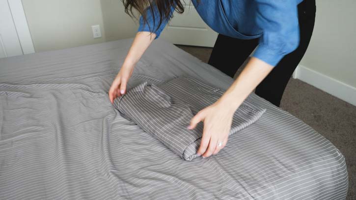 Hands folding a sheet on a bed