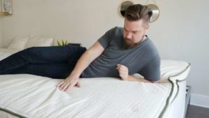 A man feels the top of a mattress topper.