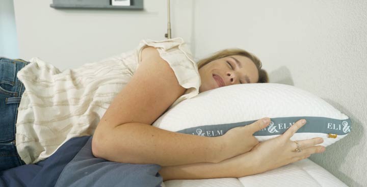 A woman sleeps on her side on an Eli and Elm Side Sleeper pillow