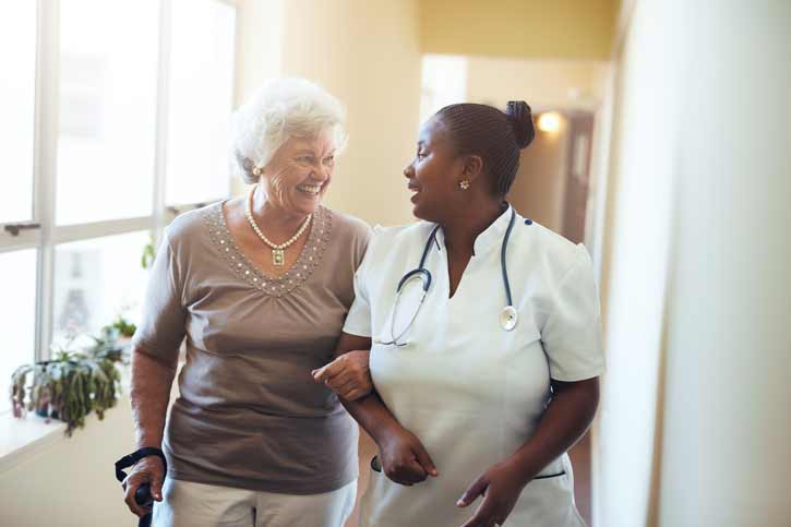 A nurse walks a patient down the hall