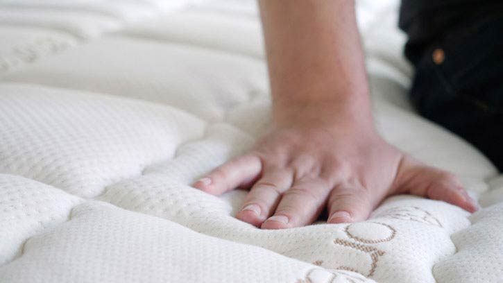 A man presses into the top of a mattress.